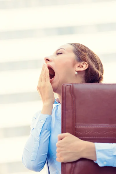 Sleepy young business woman, running to work wide open mouth yawning
