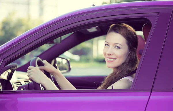 Happy woman, buckled up, driving car