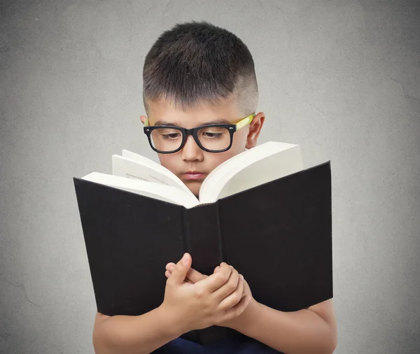 Child with glasses reading book