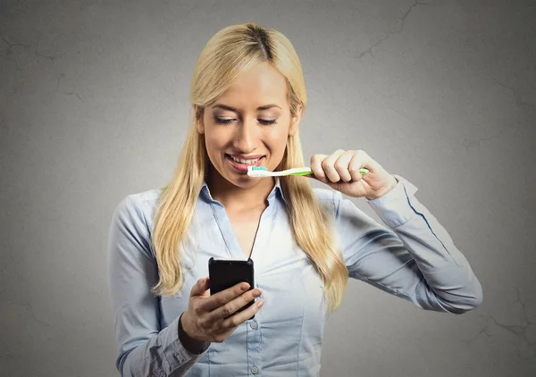 Business woman reading news on smartphone brushing teeth