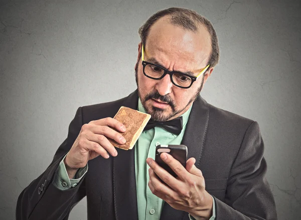 Man reading message on smart phone eating cookie