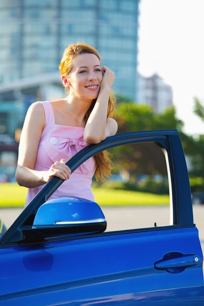 Woman buyer standing next to her new blue car