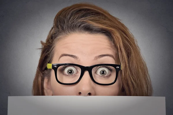 Scared surprised woman peeking over edge of blank billboard