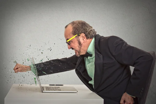 Furious businessman throws a punch into computer