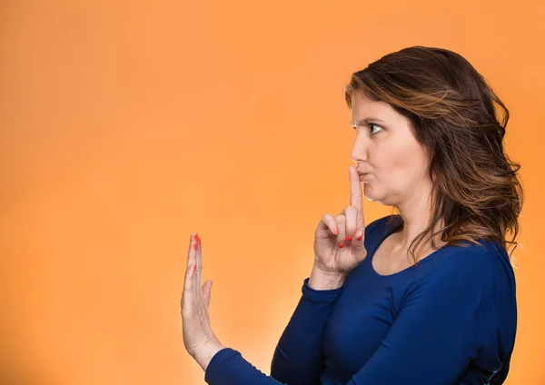 Woman with finger on lips, shhh gesture asking be quiet