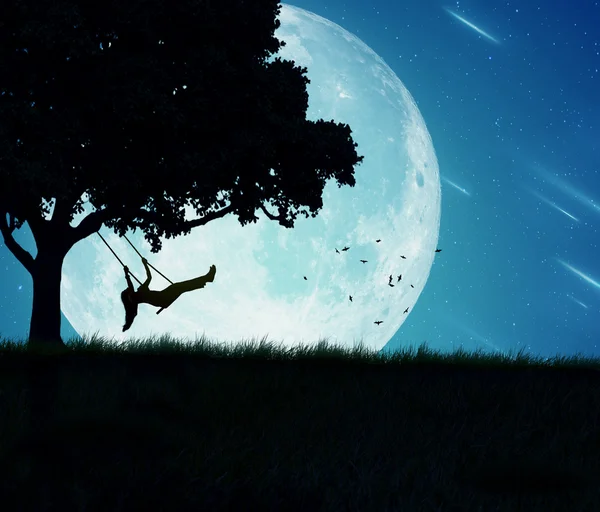 Woman swinging of a tree isolated on background of moon, earth, night skyline