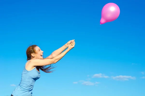 Happy smiling woman arms raised holding pink flying air balloon