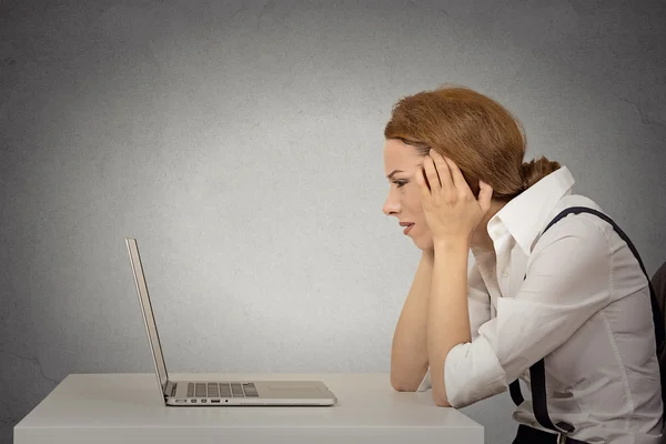 Stressed young unhappy business woman working on laptop