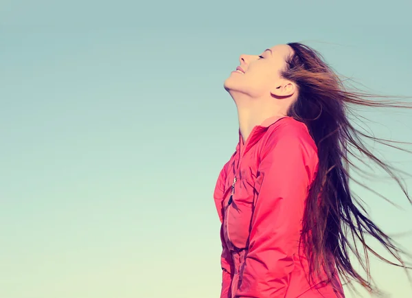 Woman smiling looking up to blue sky taking deep breath celebrating freedom.