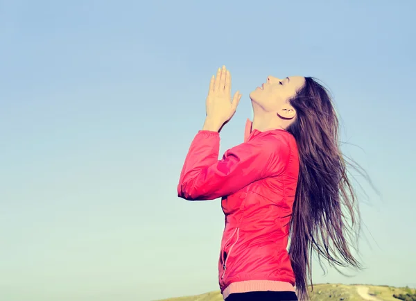 Woman arms raised up to blue sky praying thankful for freedom