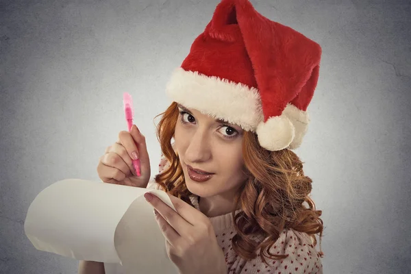 Woman with christmas hat is posing in studio writing gift ideas