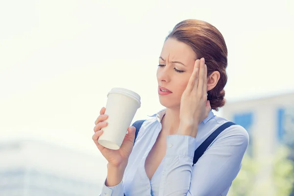 Business woman stressed by mistake having headache holding cup coffee