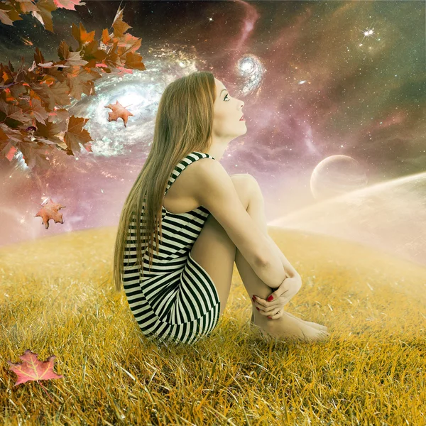 Woman sitting on meadow earth looking up at starry sky with planets