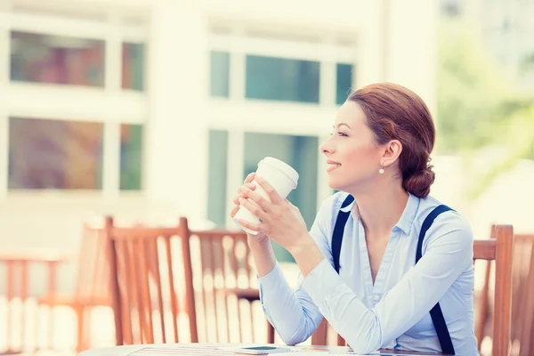 Woman drinking coffee in sun sitting outdoor
