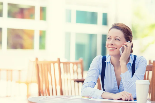 Happy woman talking on mobile phone outside office