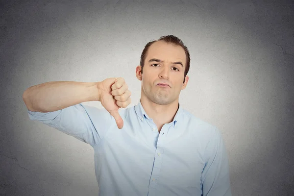 Angry, unhappy, young handsome man showing thumbs down