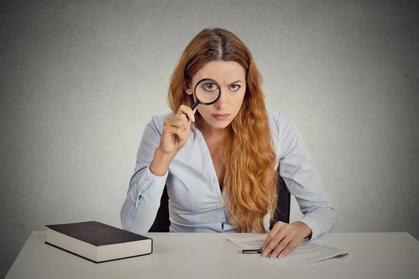Woman with glasses skeptically looking at you through magnifying glass