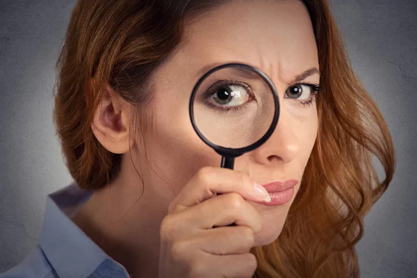 Headshot woman investigator looking through magnifying glass
