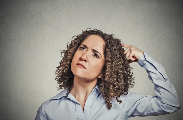 Woman scratching head thinking daydreaming about something wondering