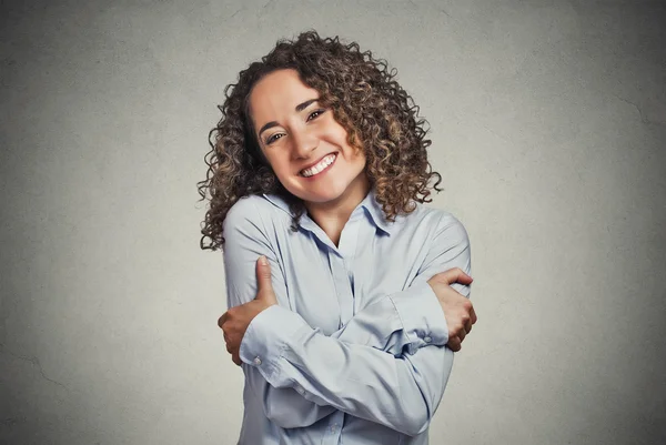 Smiling woman holding hugging herself