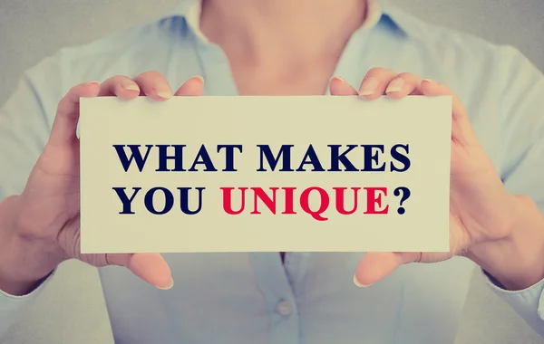 Businesswoman hands holding sign with message what Makes You Unique?