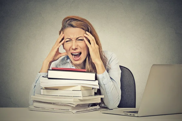 Stressed screaming woman sitting at desk with books computer