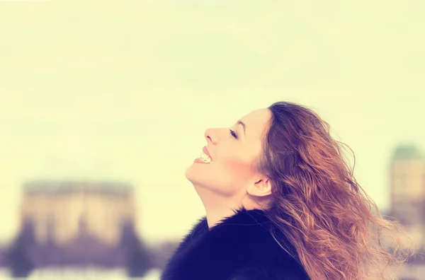 Woman smiling looking up to blue sky taking deep breath