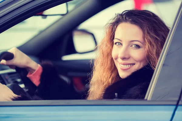 Happy winter woman, buckled up driving testing her new car