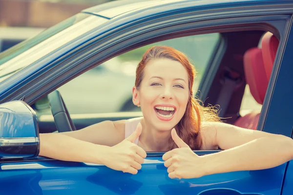 Woman driver happy smiling showing thumbs up sitting inside new car