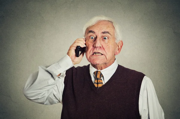 Angry senior man talking on mobile phone