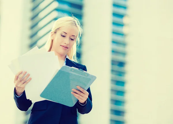 Businesswoman reading, reviewing company documents