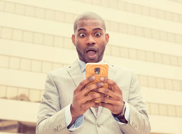 Anxious young business man looking at phone seeing bad news