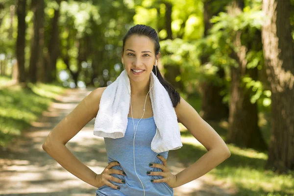 Smiling fit woman with white towel resting after sport exercises