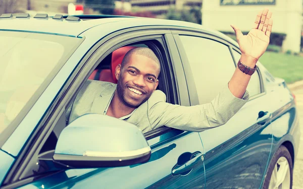 Happy young man driver stuck his hand out of the car window