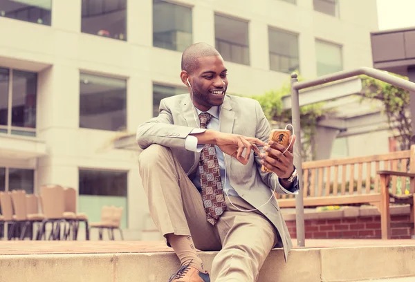 Professional man using smart phone listening to music outdoors