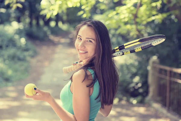 Uccessful happy young sports woman with racket walking in park