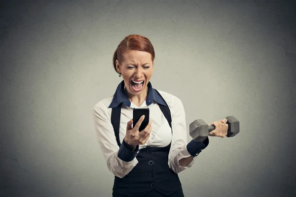 Portrait angry business woman screaming on mobile phone lifting dumbbell