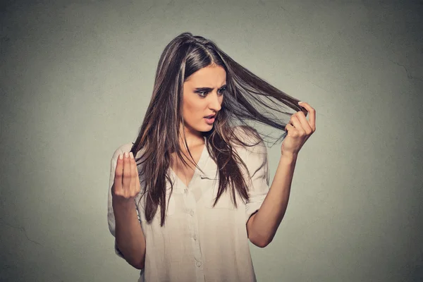 Unhappy frustrated young woman surprised she is losing hair