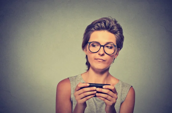 Angry woman with glasses unhappy, annoyed by something on cell phone texting