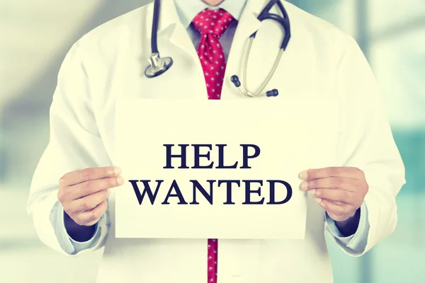 Doctor hands holding white card sign with help wanted text message