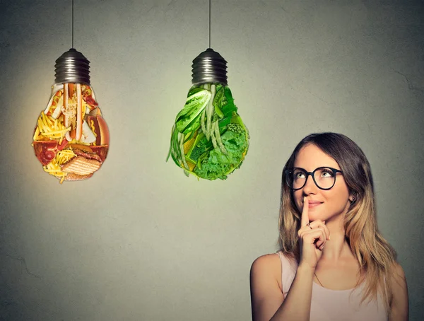 Woman thinking looking up at junk food and green vegetables shaped as light bulb