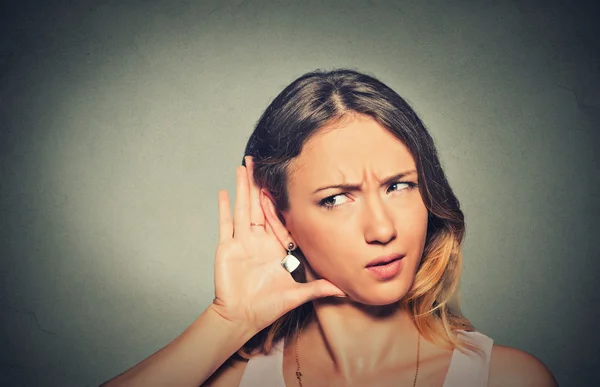 Concerned young nosy woman hand to ear gesture carefully secretly listening