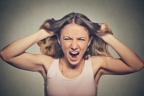 Frustrated angry woman pulling hair out yelling screaming