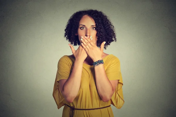 Woman covering closed mouth with hands. Speak no evil concept