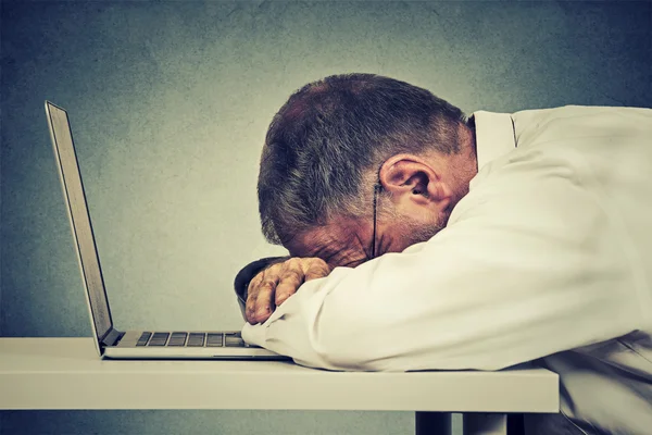 Side profile mature business man sleeping on a laptop