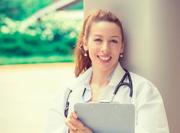 Confident female doctor medical professional standing outside ho