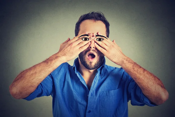 Surprised handsome man with eyes painted on his hands