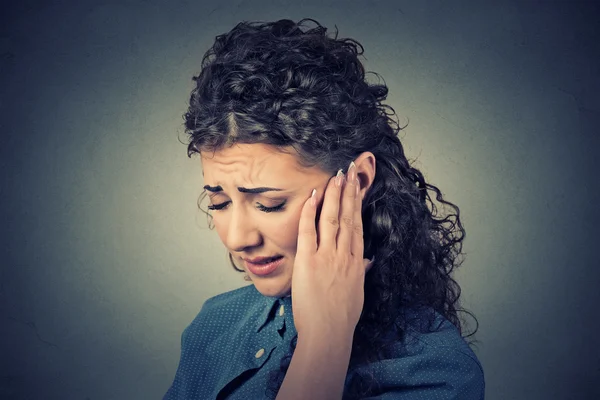 Tinnitus. Closeup sick female having ear pain touching painful head