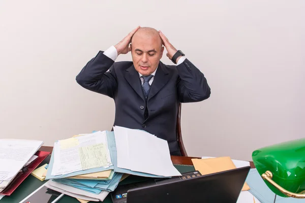 Business man at desk, deep in thought.