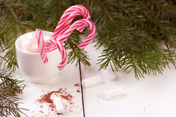 Lot of christmas red and white striped candy canes in cup with marshmallows.